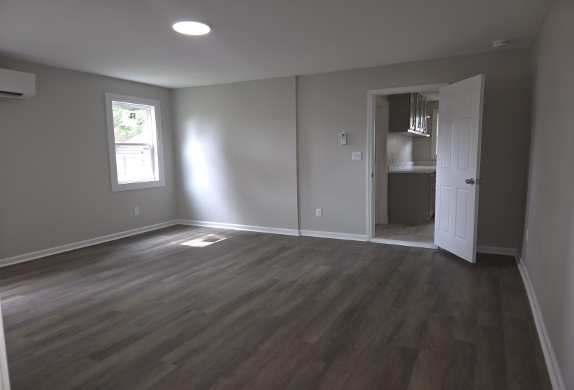 Spacious room featuring wood-finish flooring, light gray wall paint, and white trim