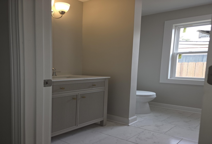 Powder room featuring a single vanity with a light gray cabinet, white countertop, and gold-tone hardware