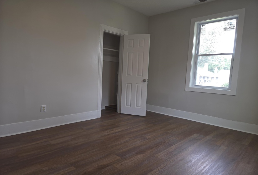 Room featuring wood-finish flooring, light grey walls, and white baseboards