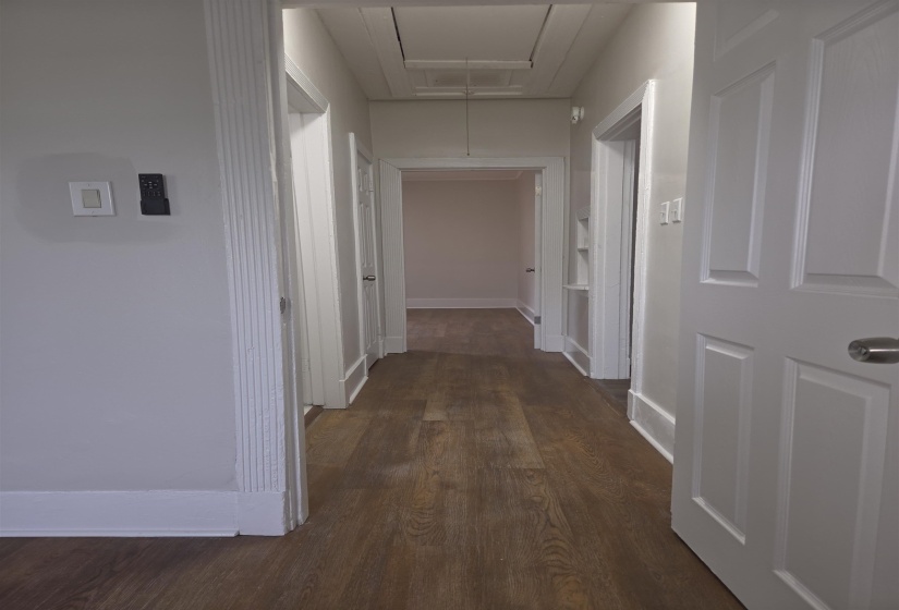 Hallway featuring wood-finish flooring, white paneled doors, and an access panel in the ceiling
