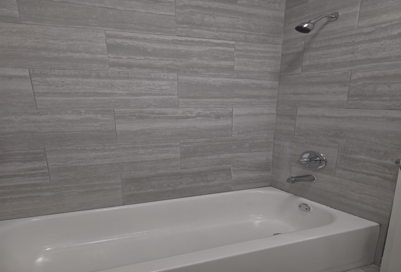 Bathtub and shower combination featuring neutral-toned tile surround