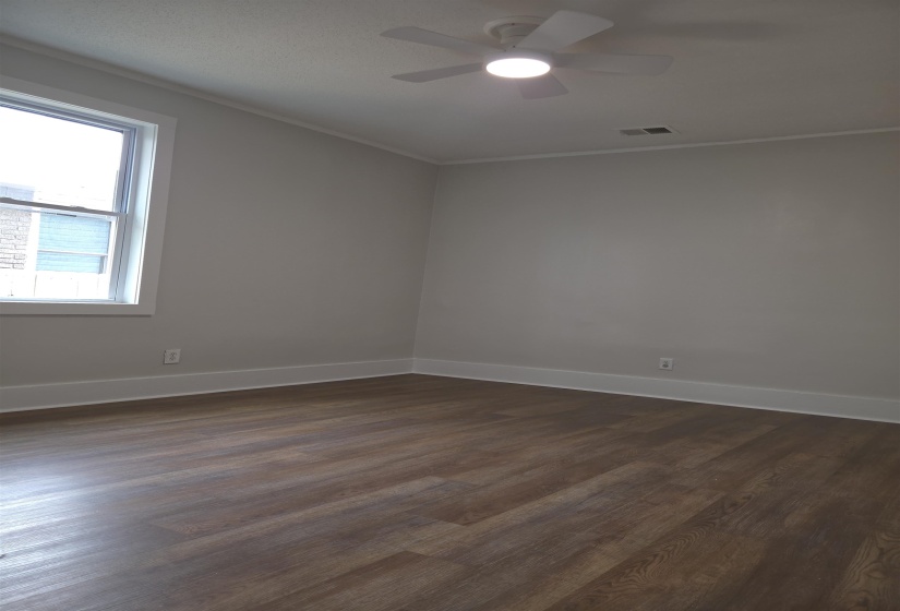 Spacious room featuring wood-finish flooring, light grey walls, and white trim