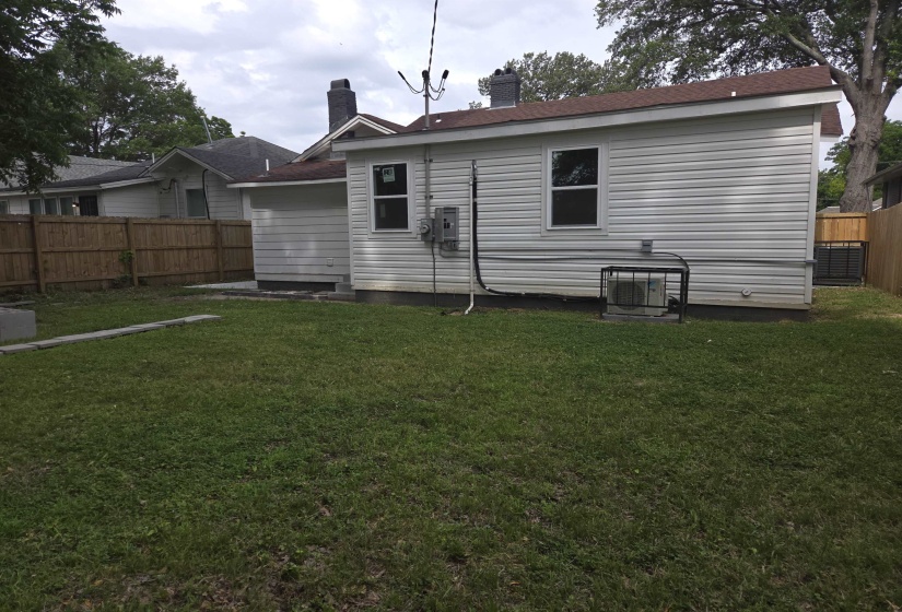 Rear exterior featuring white vinyl siding and a brown shingle roof