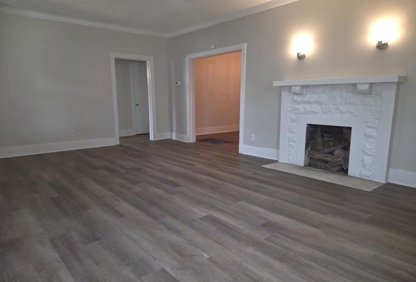 Living area featuring a white painted brick fireplace with a mantel, two sconces, and wood-finish flooring