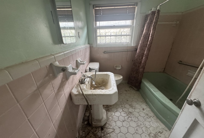 Full bathroom featuring tile walls, shower / tub combo with curtain, and wainscoting