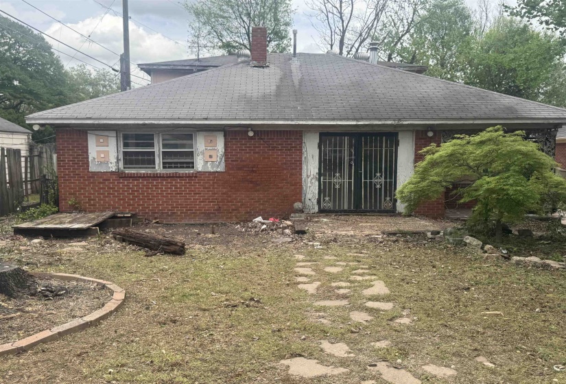Back of property featuring a chimney, a shingled roof, and brick siding