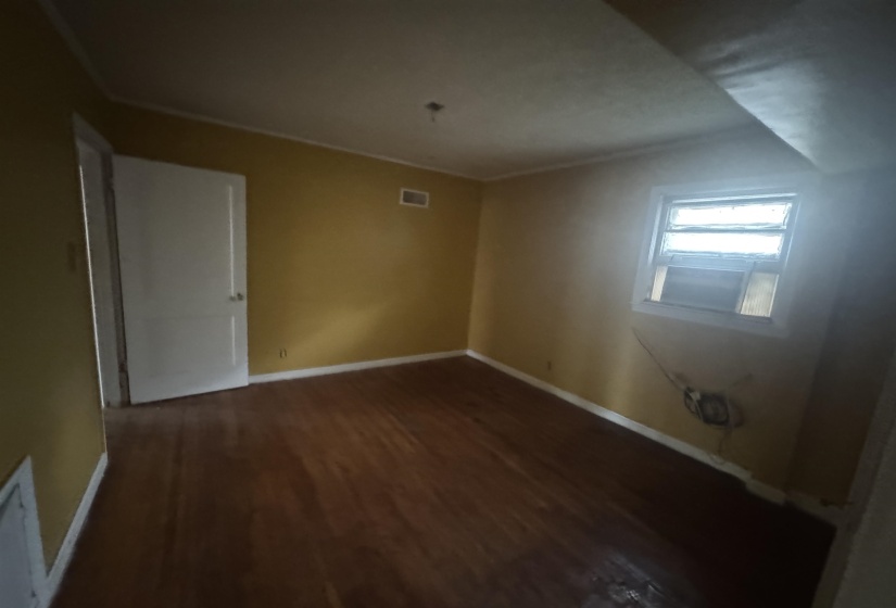 Spare room featuring dark wood-style flooring and baseboards