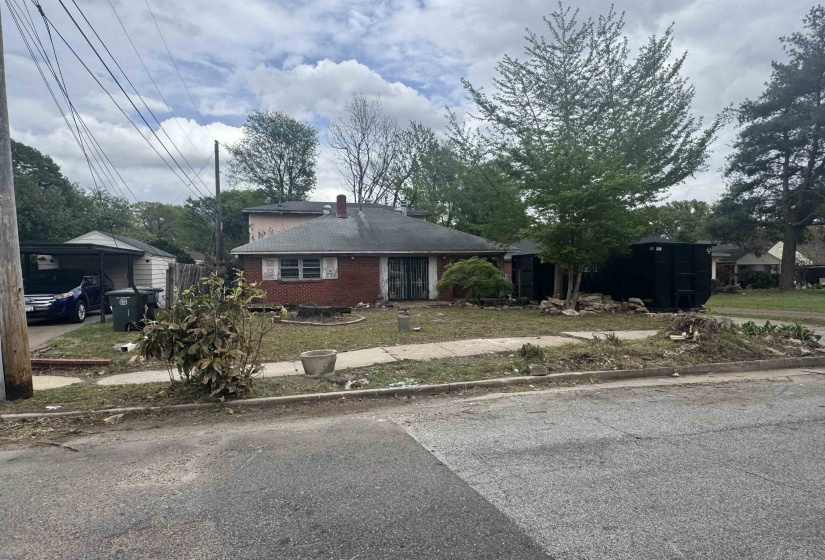 View of front of home with brick siding, a front lawn, and a chimney