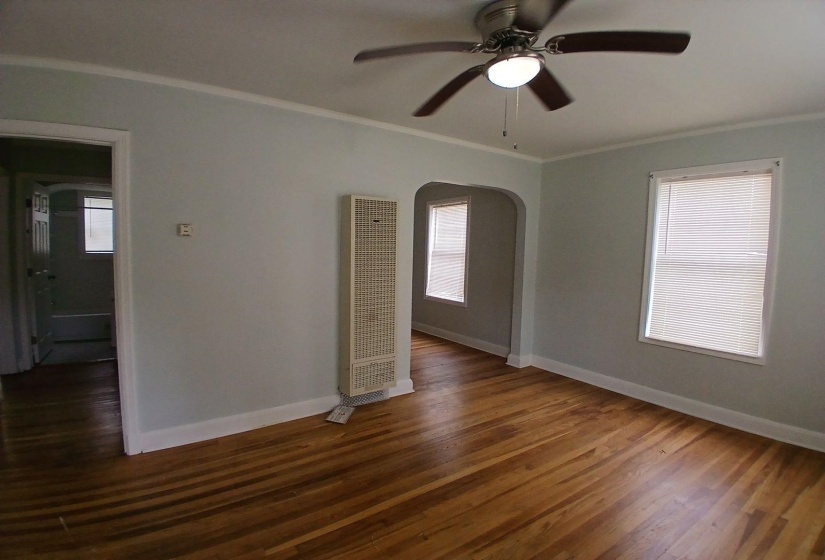 Bright interior space featuring wood-finish flooring, white baseboards, and a ceiling fan with integrated lighting
