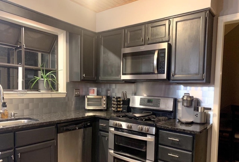 Modern kitchen featuring dark cabinetry with granite countertops
