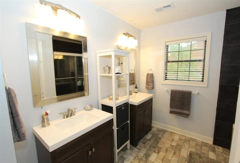 Bathroom featuring dual vanities with white countertops and dark wood-finish cabinetry