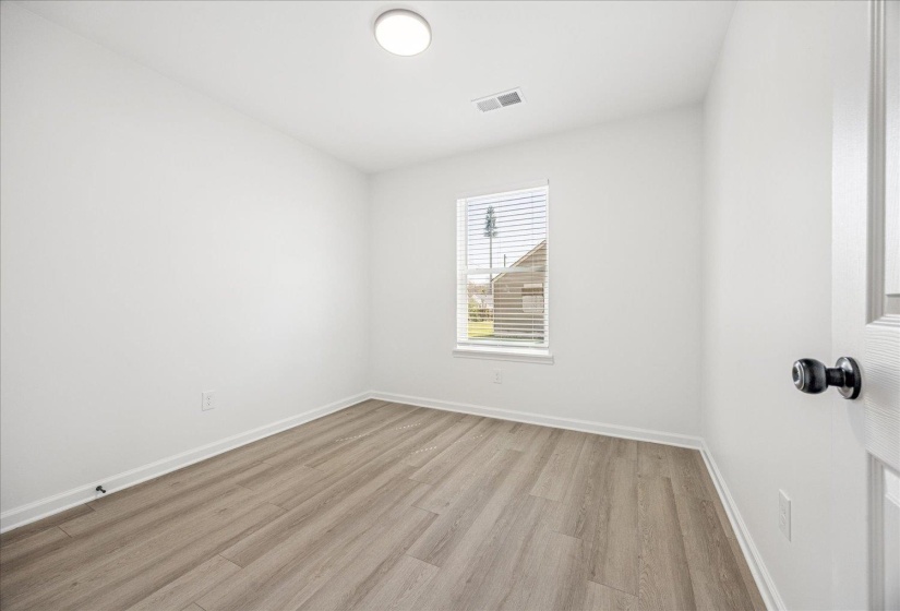 Room featuring light wood-finish flooring, white walls, and a window with blinds