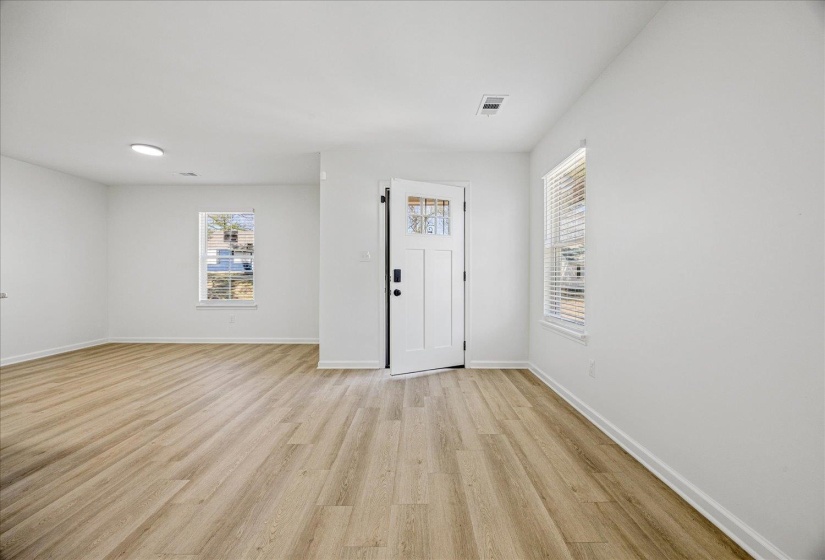 Entryway featuring a white paneled door with frosted glass accents, light wood-finish flooring, white baseboards, and two windows with blinds