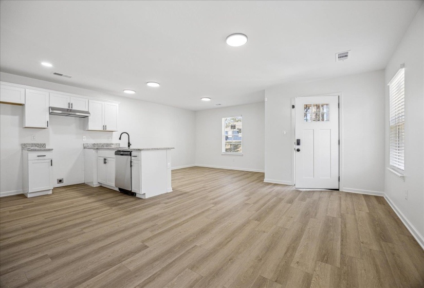 Open-concept living area featuring wood-finish flooring, recessed lighting, and a kitchen island with integrated sink