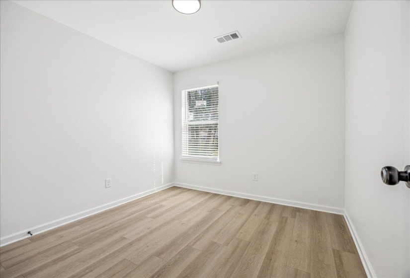 Compact room featuring wood-finish flooring, white baseboards, and a single window with blinds