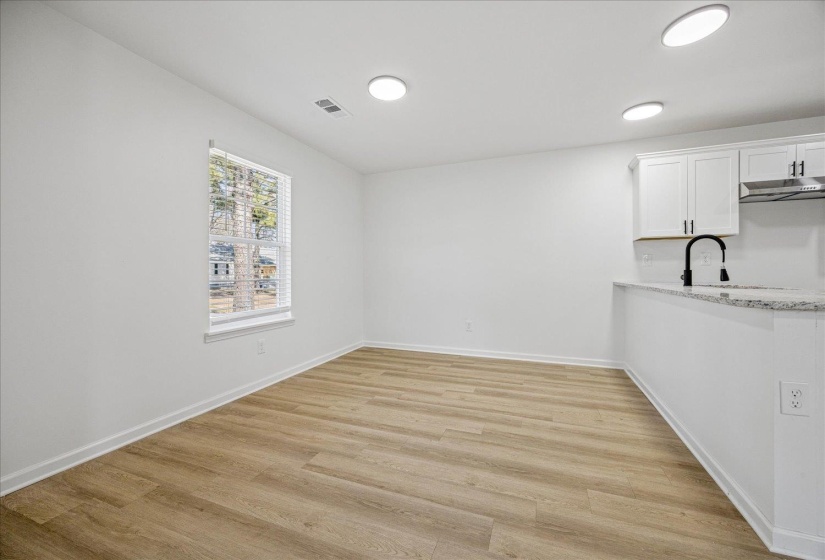 Open-concept living area featuring wood-finish flooring, recessed lighting, and a window with blinds