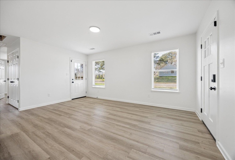Open-concept living space with light wood-finish flooring, white walls, and recessed lighting