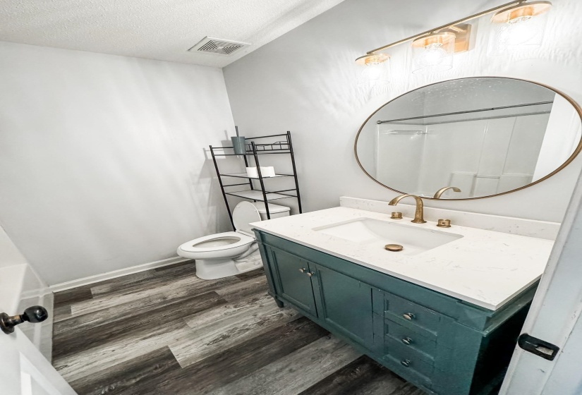 Bathroom with wood finished floors, vanity, and a textured ceiling