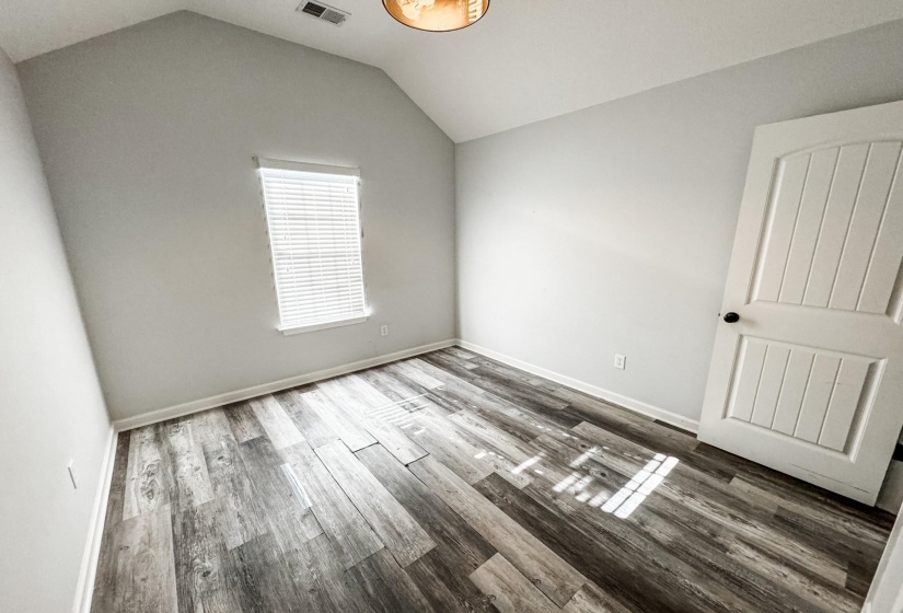 Unfurnished bedroom featuring wood finished floors and lofted ceiling