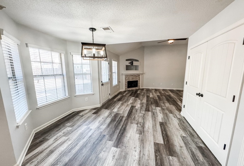 Unfurnished living room with a textured ceiling, dark wood-type flooring, a ceiling fan, and a stone fireplace