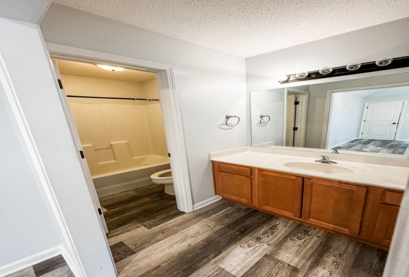 Bathroom with wood finished floors, vanity, a textured ceiling, and shower / tub combination