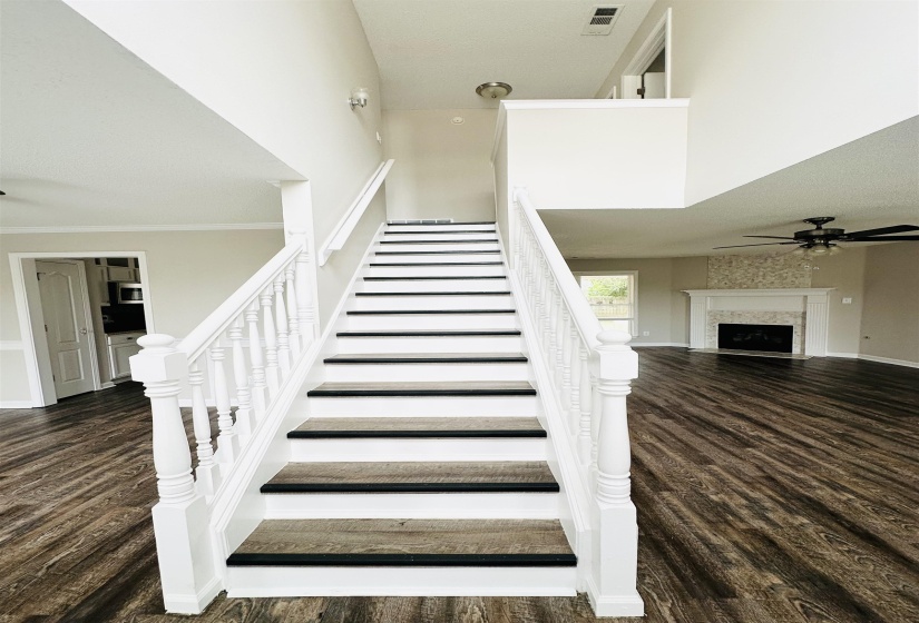 Two-story foyer featuring a wood-finish staircase with white risers and balusters