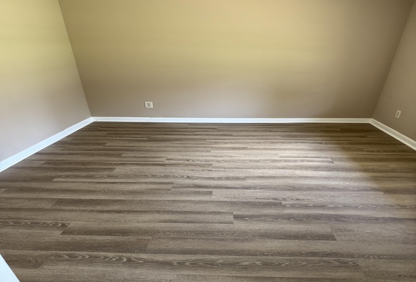 Interior room featuring wood-finish flooring, light beige wall paint, and white baseboards