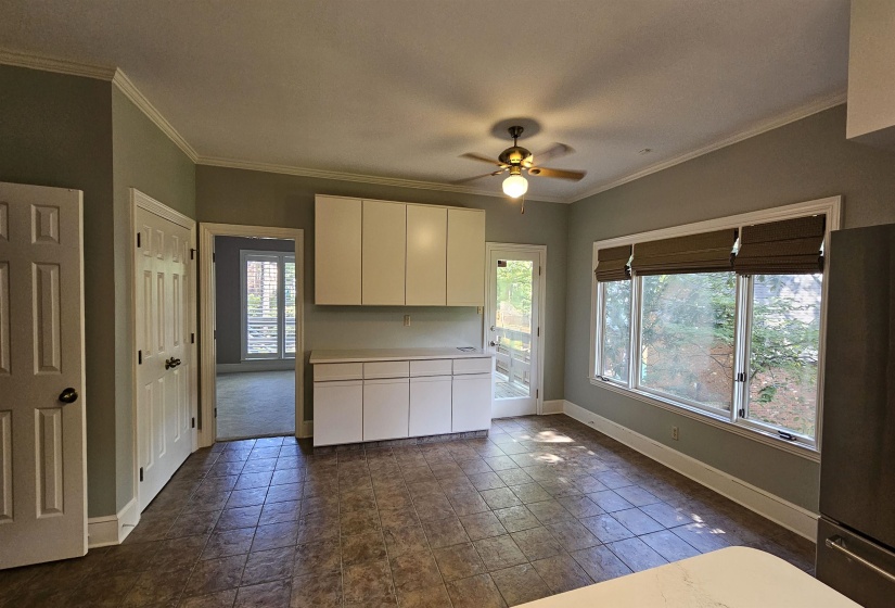 Eat-in kitchen area featuring tile flooring, white cabinetry, a ceiling fan with integrated lighting, and multiple windows with Roman shades