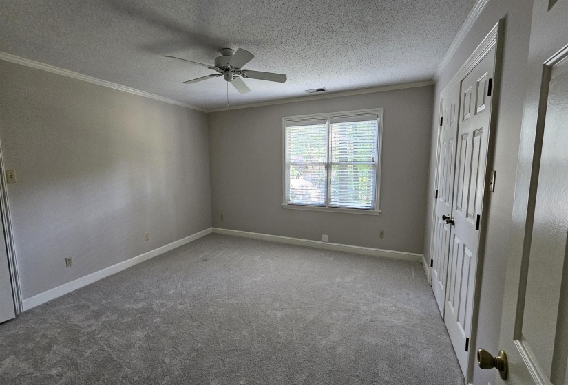 Spacious room featuring neutral carpeting and light-toned walls with crown molding
