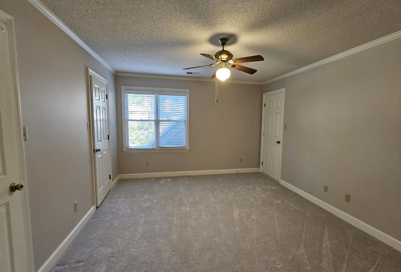 Spacious room featuring neutral carpeting, light neutral wall paint, and white crown molding