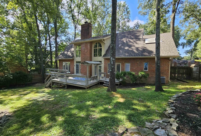Brick exterior with a multi-level wooden deck featuring a built-in spa