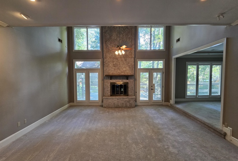 Living space featuring a stone fireplace with a raised hearth, high ceilings, carpet flooring, and recessed lighting