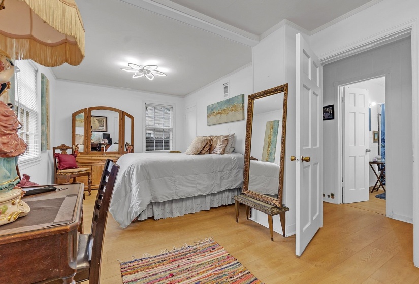 Bedroom featuring wood-finish flooring, two windows with blinds, a modern ceiling light fixture, and a paneled interior door