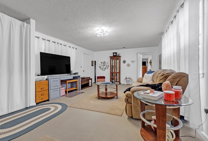 Spacious room featuring light-colored flooring, white walls, and a textured ceiling