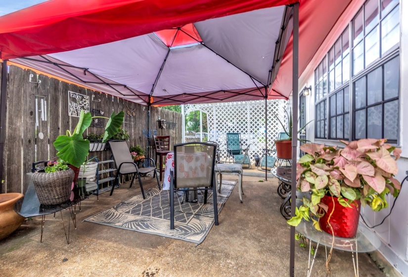 Private patio with concrete flooring, accented by a tall wooden fence and white lattice detailing
