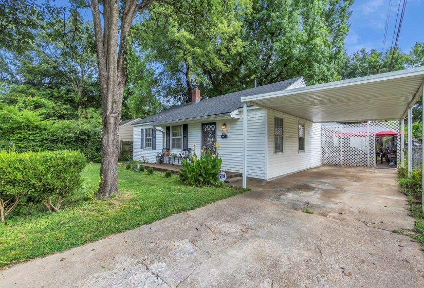 White siding residence featuring a covered front porch, an attached carport, and a concrete driveway