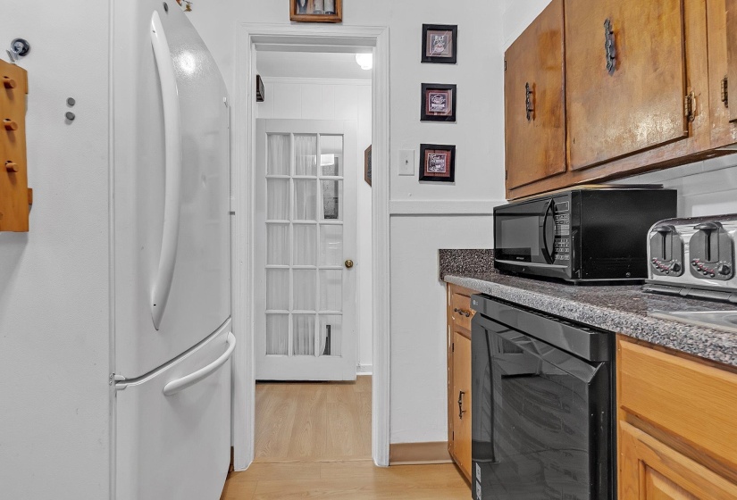 Kitchen area featuring wood-finish cabinetry, speckled countertops, and a built-in dishwasher