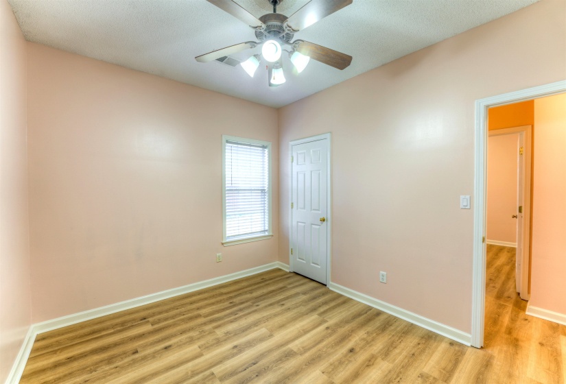 Room featuring wood-finish flooring, a ceiling fan with integrated lighting, and a window with blinds