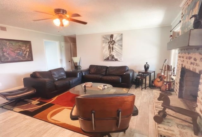 Living room featuring a brick fireplace, crown molding, and light wood-type flooring