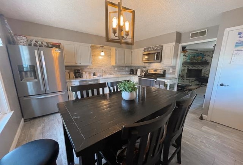 Dining space with sink, light hardwood / wood-style flooring, a textured ceiling, and ceiling fan with notable chandelier