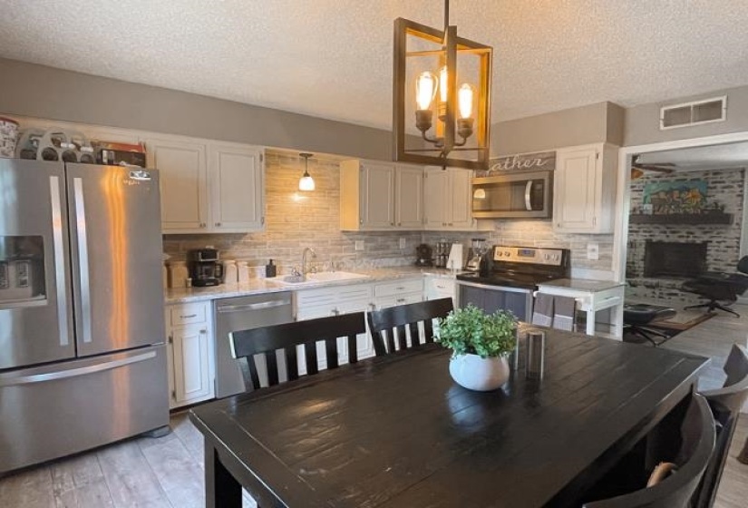Dining area with light hardwood / wood-style floors, a brick fireplace, sink, and a textured ceiling