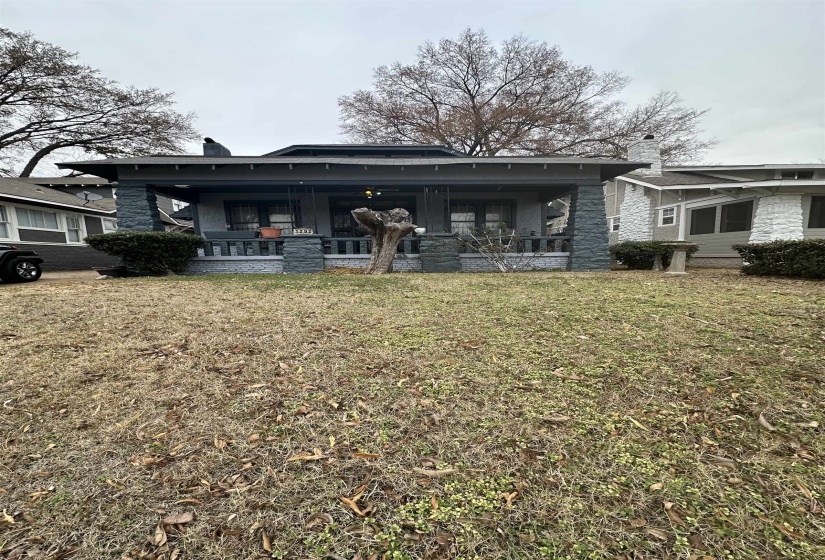 View of front of house with a chimney, a front yard, and stone siding