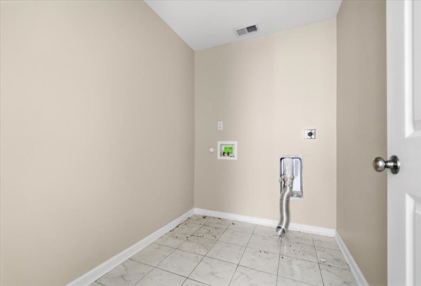 Utility room with neutral-toned walls, white baseboards, and light-colored tile flooring