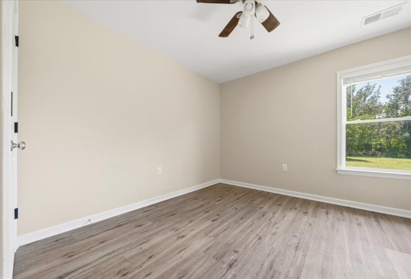 Room featuring wood-finish flooring, a ceiling fan, and a window with blinds