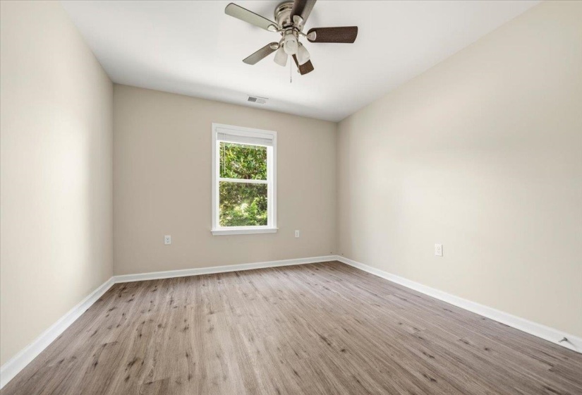 Bedroom featuring wood-finish flooring, neutral wall tones, a ceiling fan with light fixture, and a window with a white frame