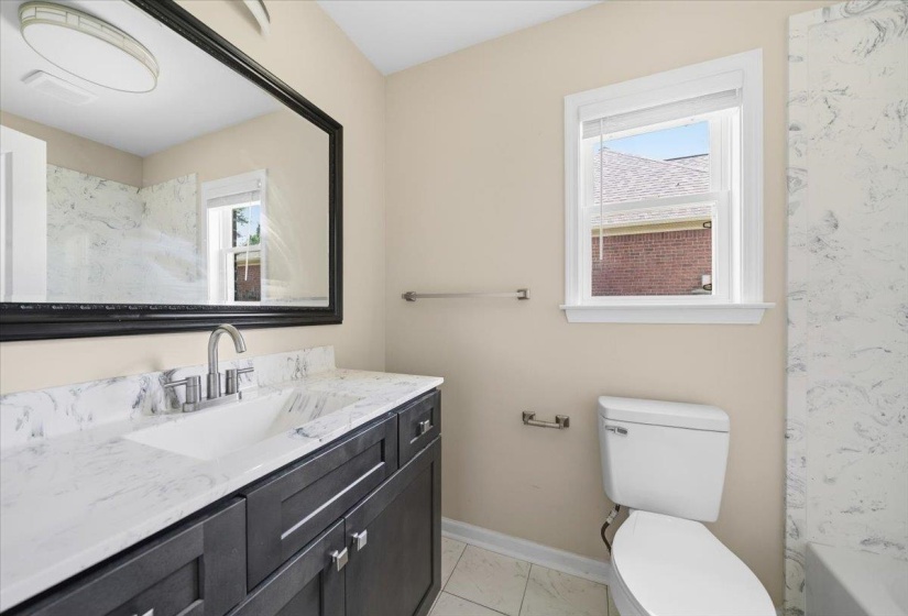 Bathroom vanity with a white countertop and integrated sink, chrome faucet, and dark wood-finish cabinetry