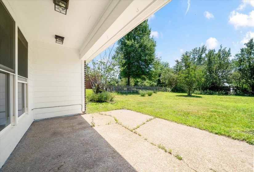 Covered patio area with concrete flooring, white siding, and two ceiling-mounted light fixtures