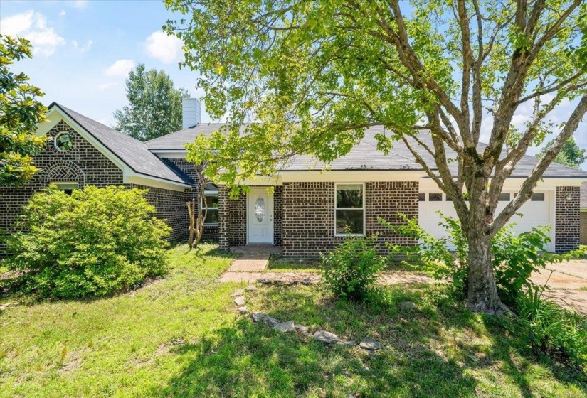 Brick exterior residence with a white front door, multiple windows, and two white garage doors