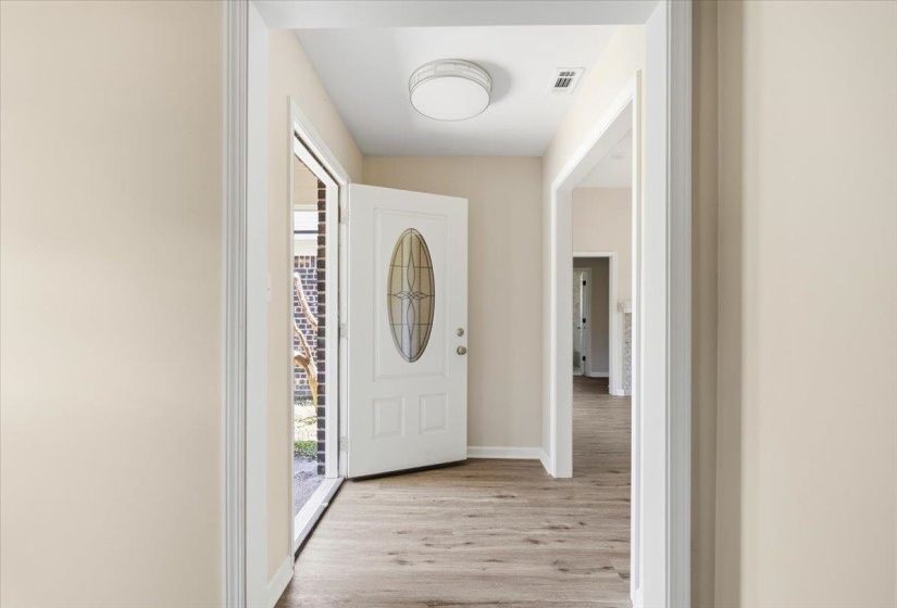 Entryway featuring wood-finish flooring, light-toned wall paint, a white door with an oval decorative glass insert, white trim, and a flush-mount ceiling light