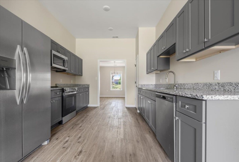 Kitchen featuring wood-finish flooring, stainless steel appliances, grey cabinetry, and speckled countertops